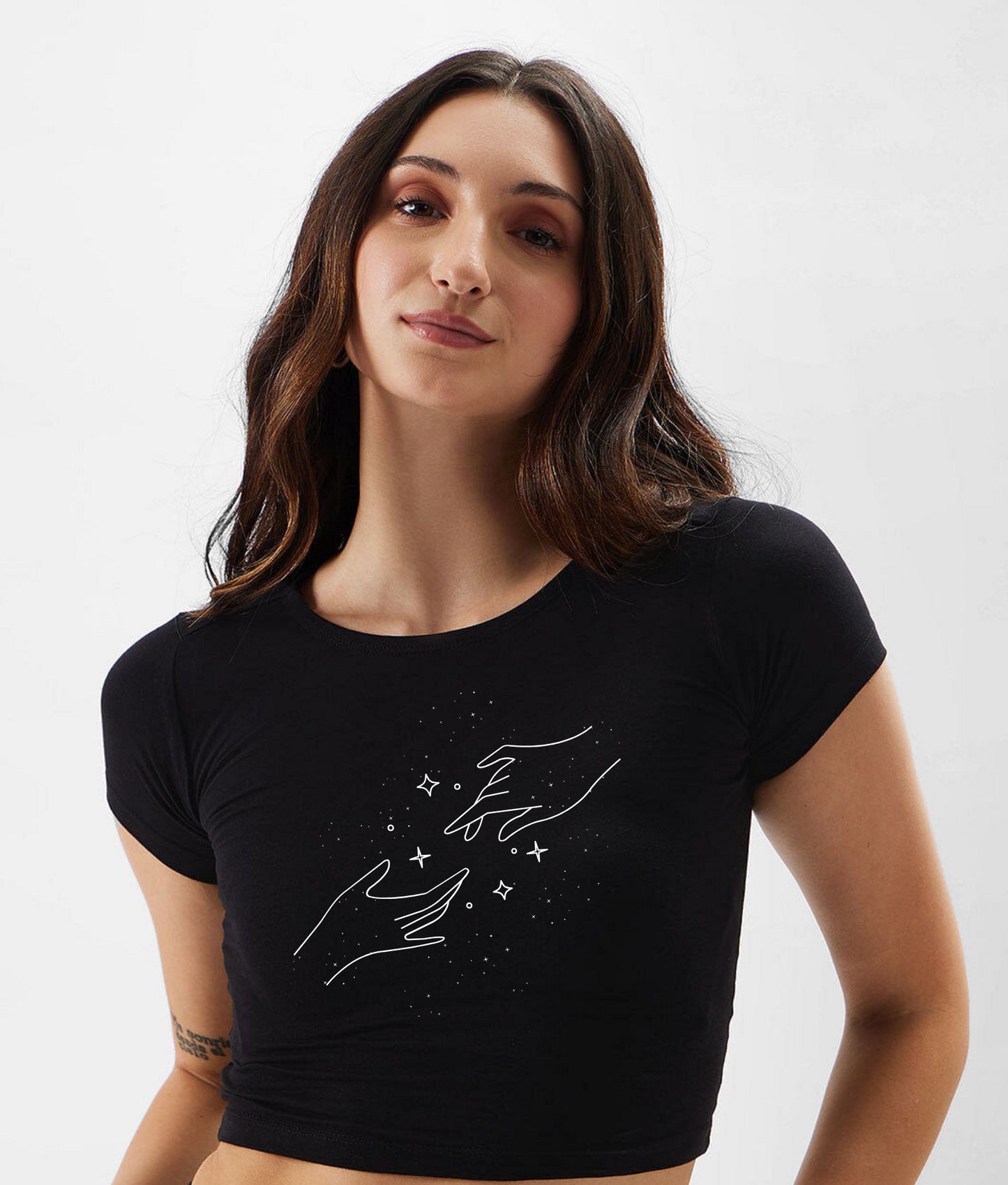 Woman wearing a black crop top with white graphic design on a plain background