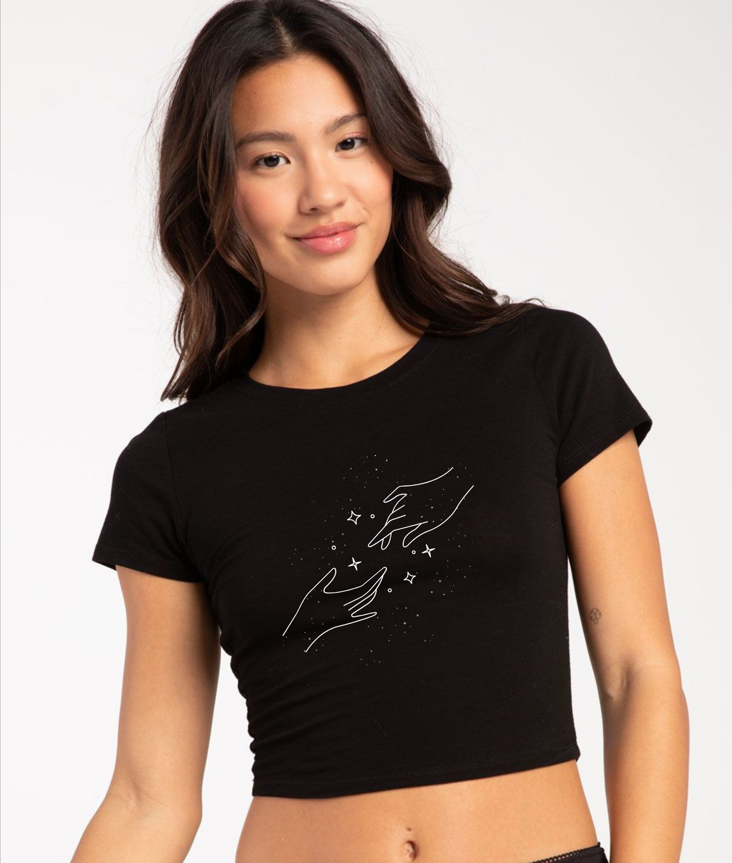 Woman wearing a black crop top with a design on a plain background